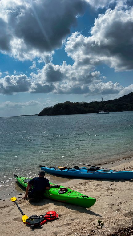 Kayaks on a beach with a hilly headland behind